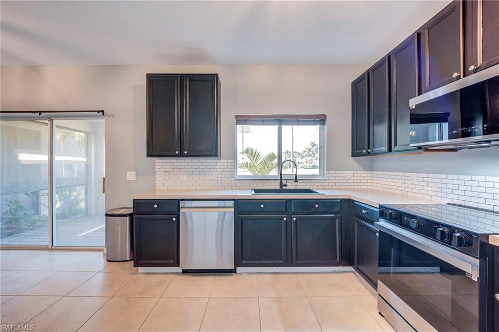 Kitchen featuring stainless steel appliances, tasteful backsplash, light stone countertops, and light tile patterned floors