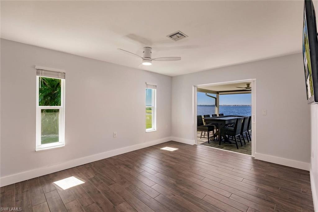 Spare room with ceiling fan, dark wood-style flooring, plenty of natural light, and visible vents