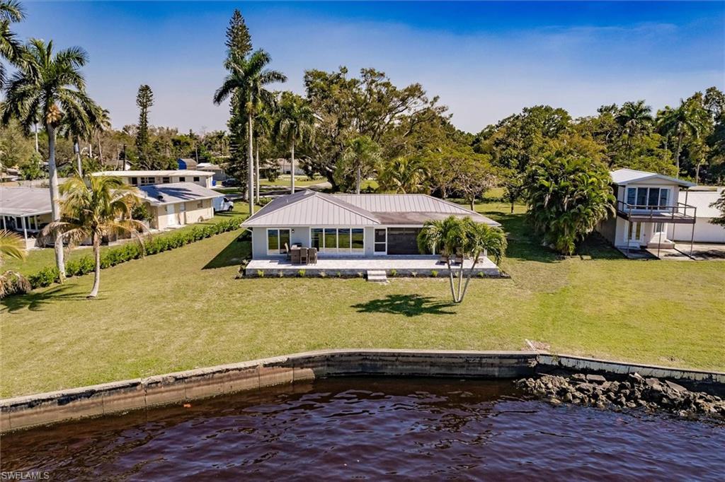 Back of property featuring a patio area, a water view, and a lawn