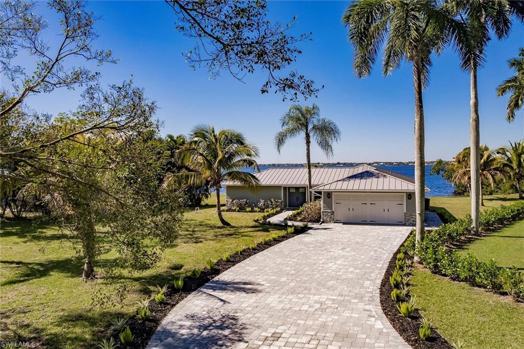 Ranch-style house with metal roof, an attached garage, a water view, decorative driveway, and a front yard