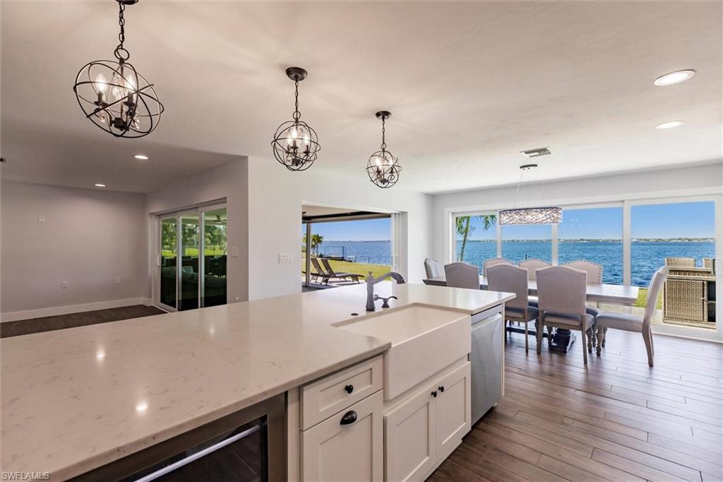Kitchen featuring decorative light fixtures, a water view, light stone countertops, stainless steel dishwasher, and a sink