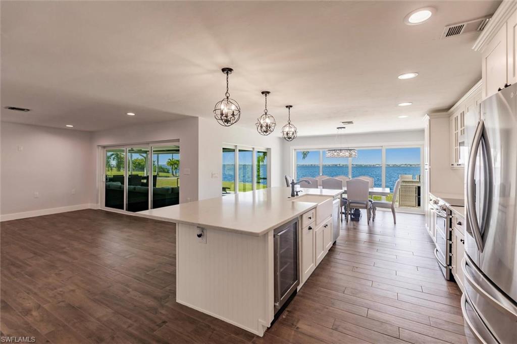 Kitchen featuring a water view, a center island with sink, appliances with stainless steel finishes, and white cabinets