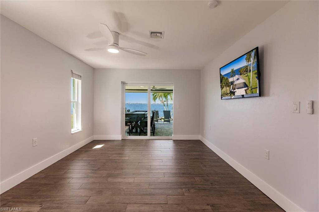 Empty room featuring dark wood-style floors, visible vents, ceiling fan, and baseboards