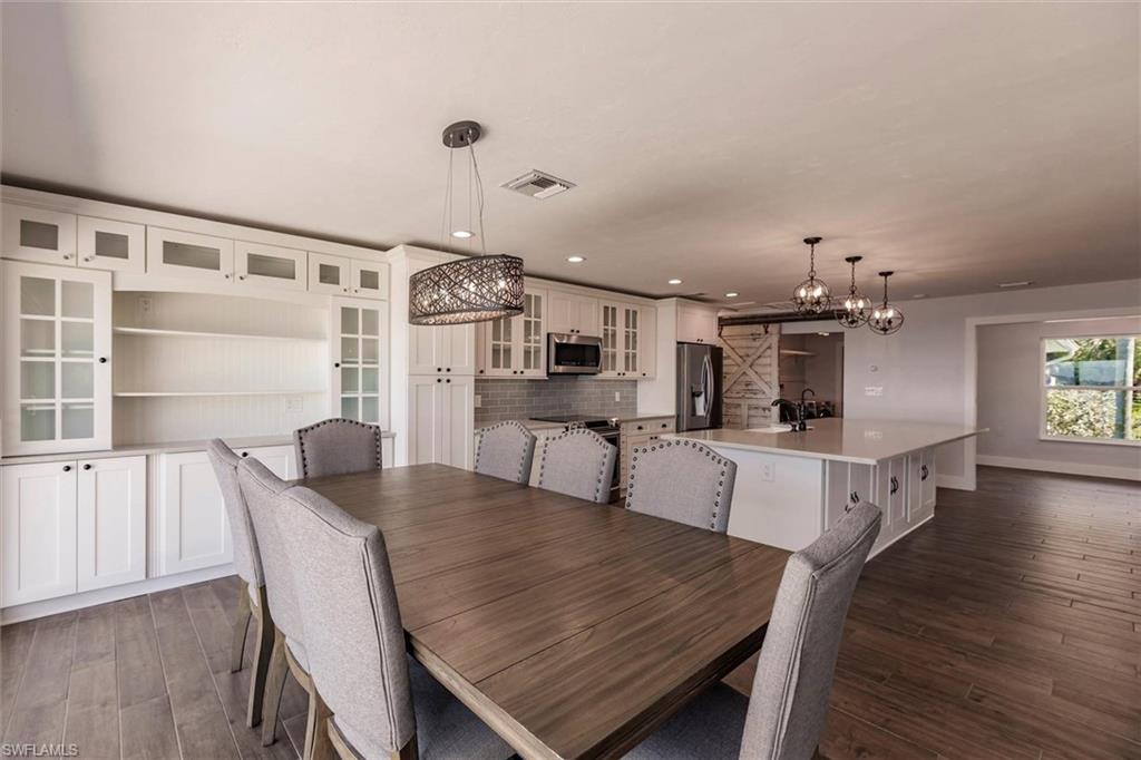 Dining area featuring dark wood-style flooring, recessed lighting, visible vents, and baseboards