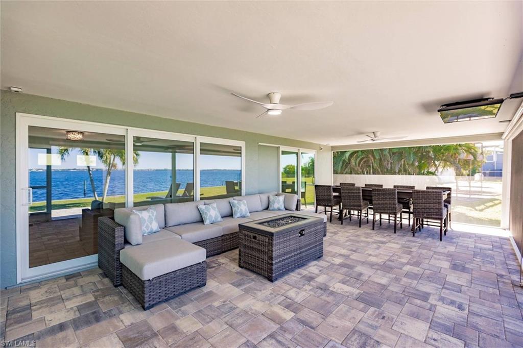 View of patio with a ceiling fan, outdoor dining space, an outdoor living space with a fire pit, and a water view