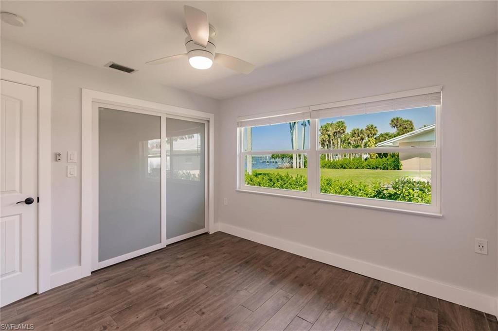 Unfurnished bedroom featuring visible vents, dark wood finished floors, baseboards, and multiple windows