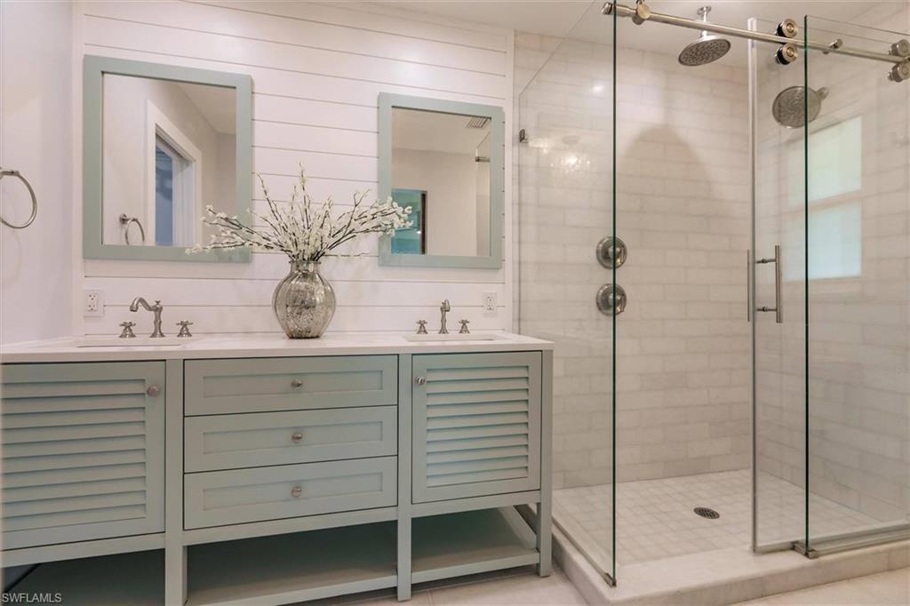 Bathroom featuring a stall shower, a sink, and double vanity