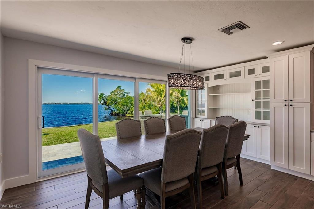 Dining room with a water view, dark wood finished floors, visible vents, and recessed lighting
