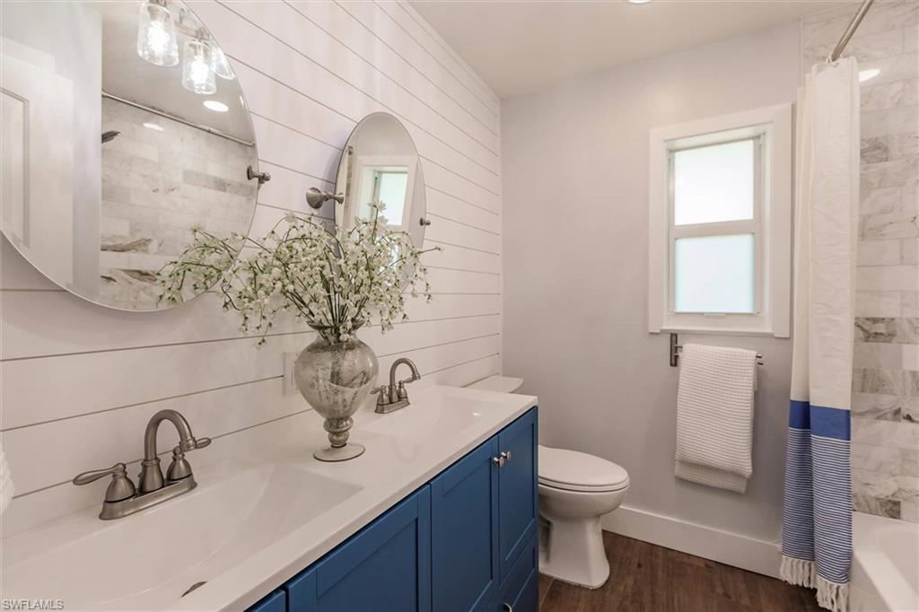 Bathroom with double vanity, shower / bath combo, a sink, and wood finished floors