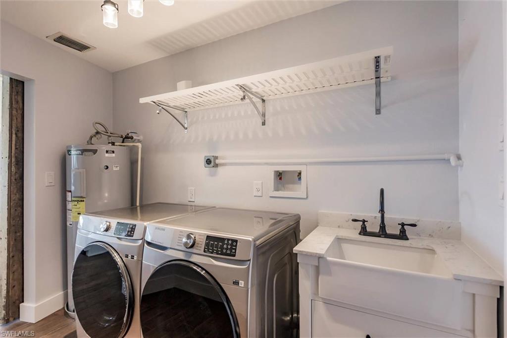 Washroom with laundry area, a sink, visible vents, washer and dryer, and light wood finished floors