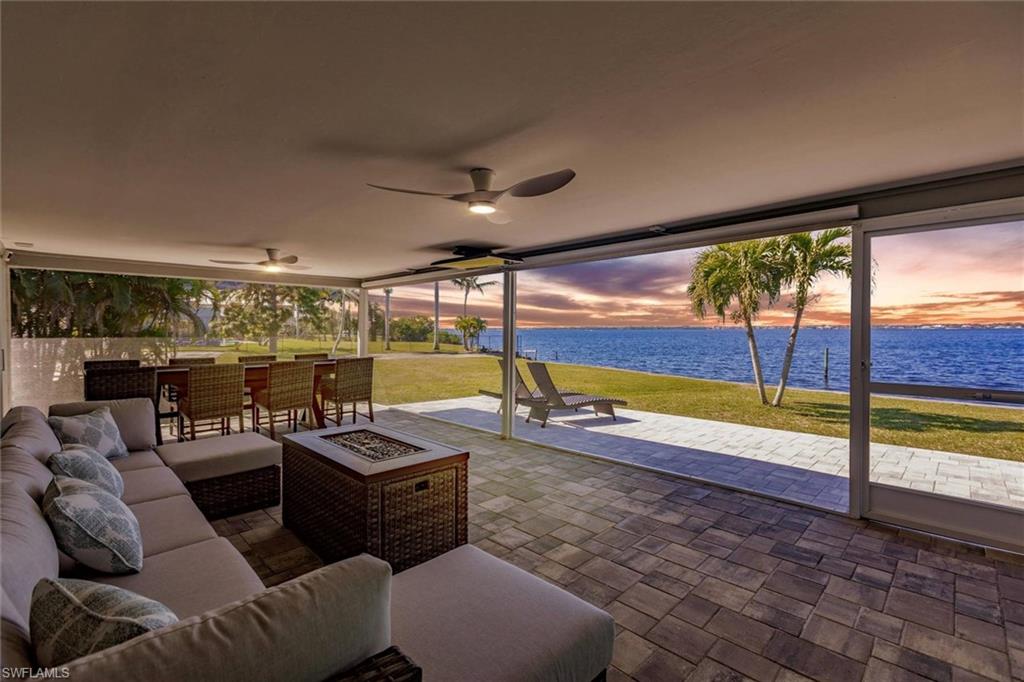 View of patio / terrace featuring a ceiling fan, an outdoor living space with a fire pit, and a water view