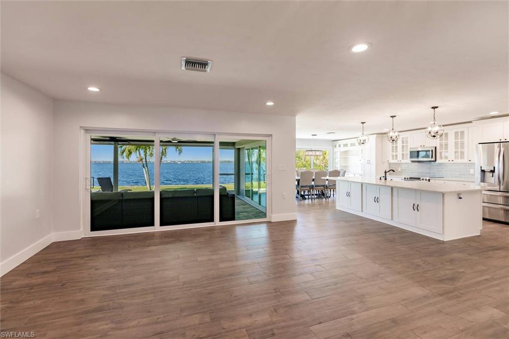 Unfurnished living room featuring a water view, visible vents, dark wood finished floors, and recessed lighting