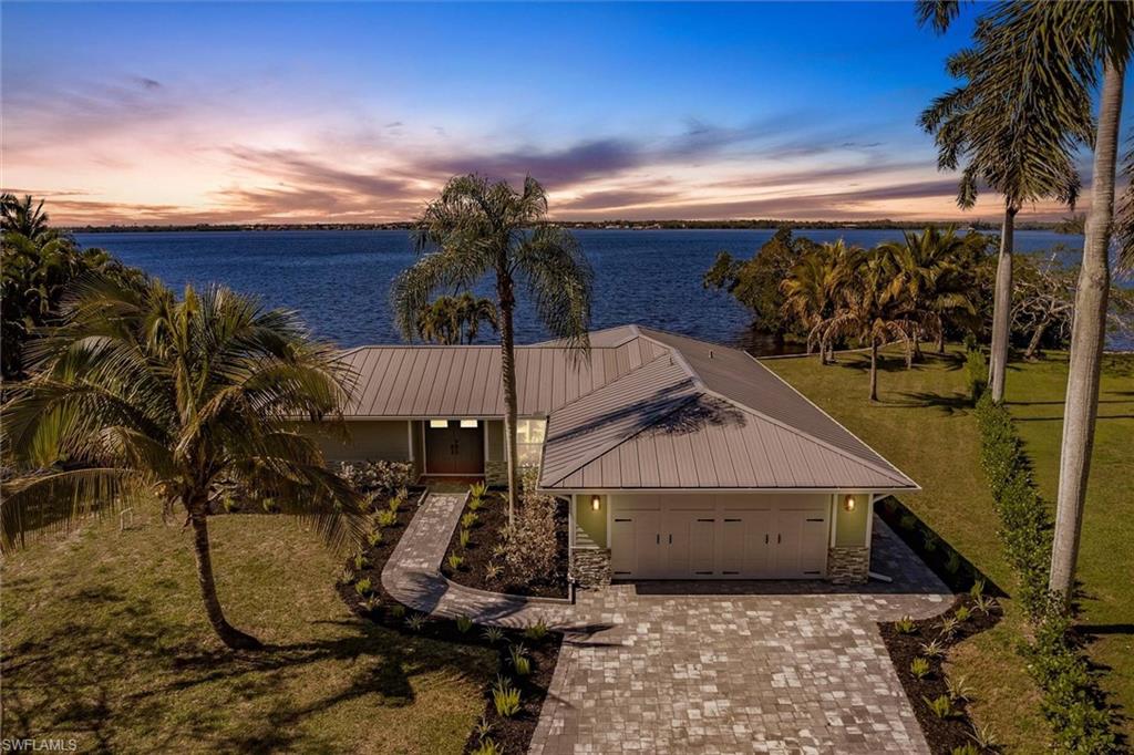 View of front facade with an attached garage, metal roof, decorative driveway, and a water view