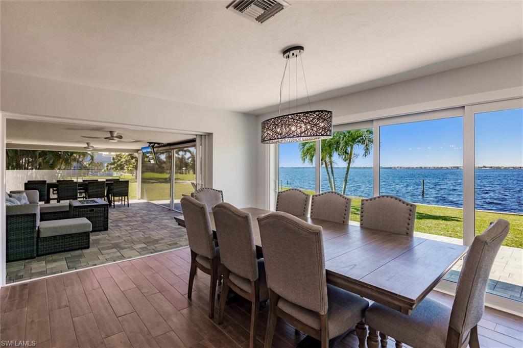 Dining area with dark wood-type flooring, a water view, visible vents, and a ceiling fan