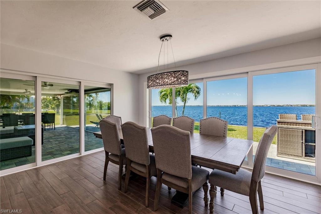 Dining room featuring dark wood-type flooring, a water view, and visible vents