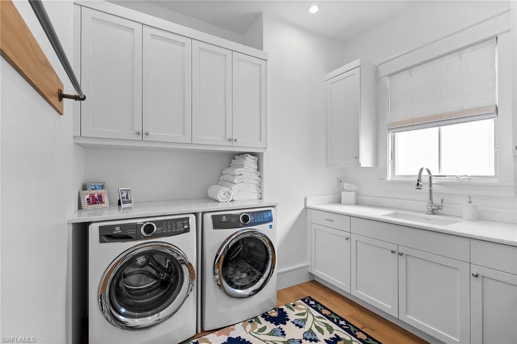 Laundry room with light wood-style flooring, independent washer and dryer, and cabinet space