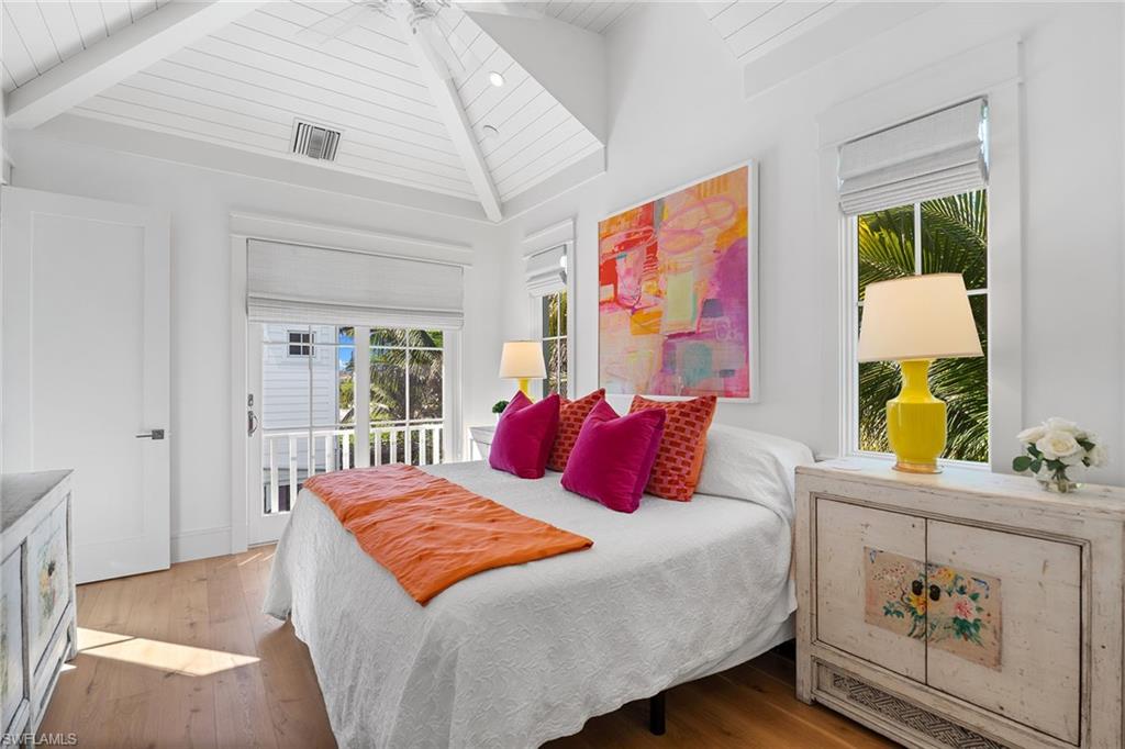 Bedroom with access to outside, wood-type flooring, and a high wooden beamed ceiling
