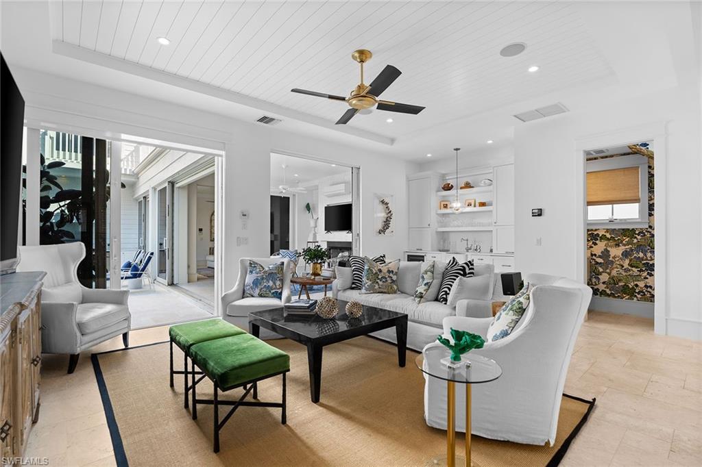 Living area featuring a wood tray ceiling, a ceiling fan, recessed lighting, and light stone finish flooring