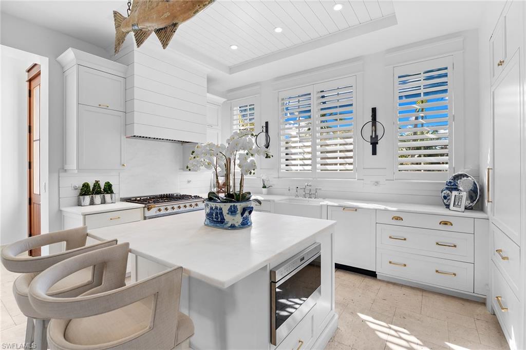Kitchen featuring white cabinets, a kitchen bar, a kitchen island, stainless steel microwave, and a tray ceiling