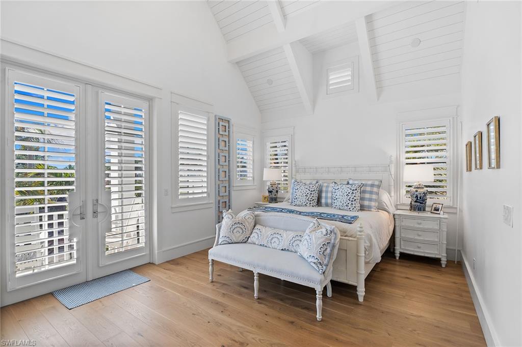 Bedroom featuring access to outside, light wood-style flooring, and a high wooden beamed ceiling