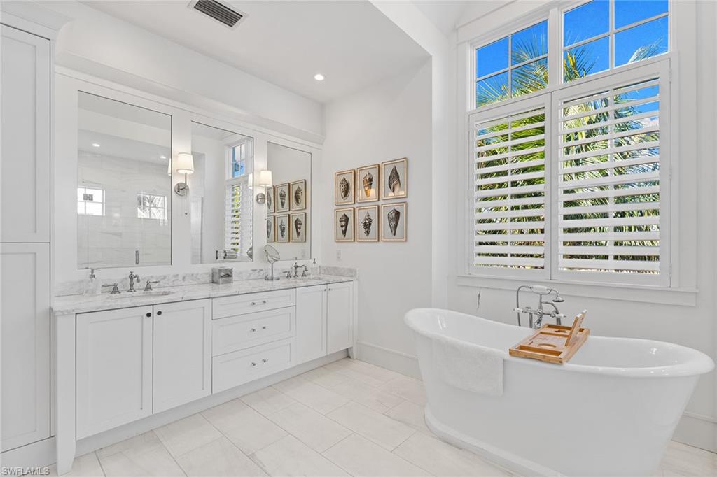Full bathroom featuring double vanity, a soaking tub, and a shower stall