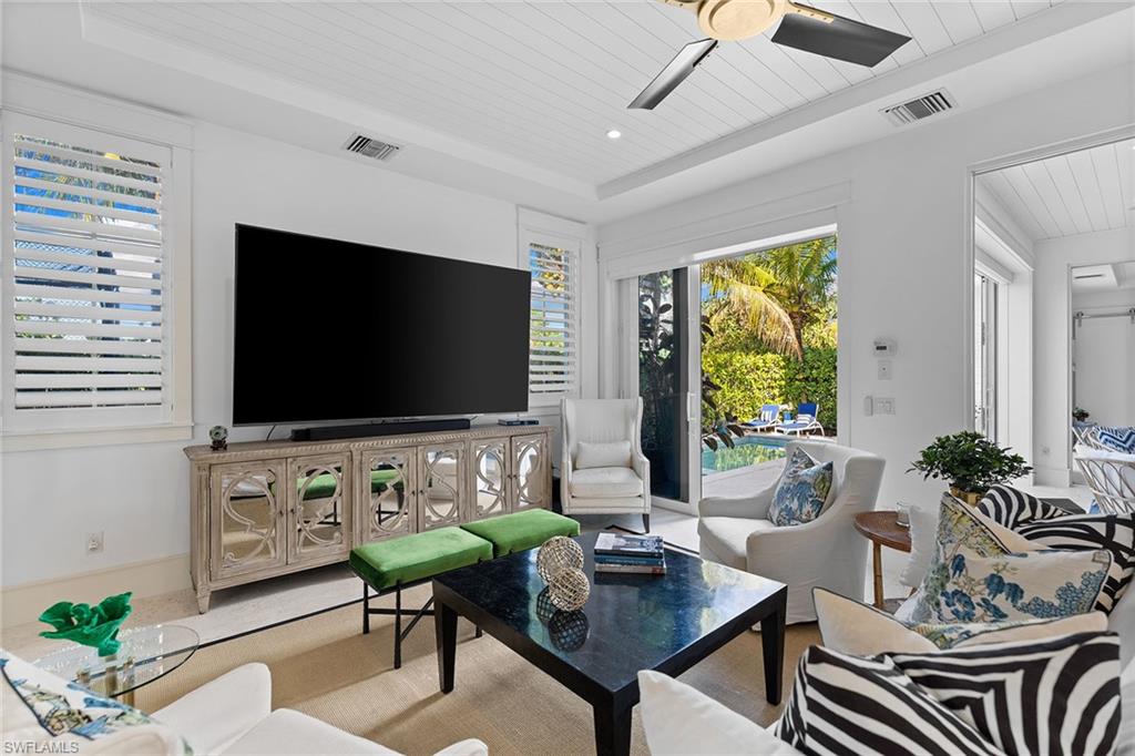 Living room with a wood tray ceiling, a ceiling fan, and plenty of natural light