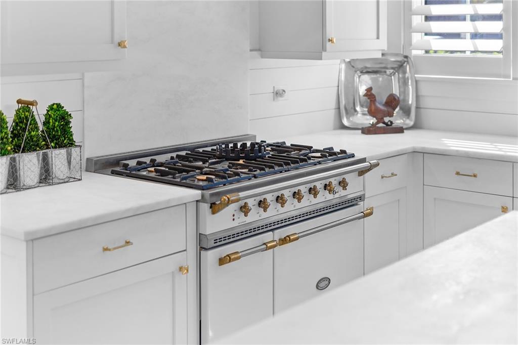 Kitchen featuring range with two ovens, white cabinetry, and light stone countertops