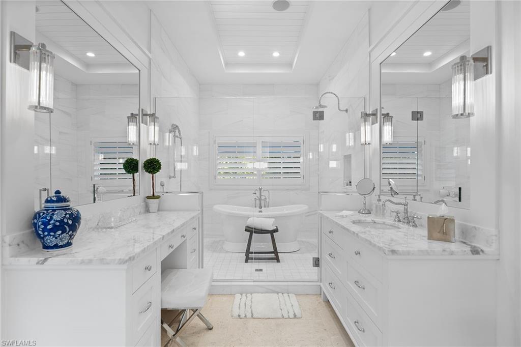 Full bath with vanity, a raised ceiling, and a soaking tub
