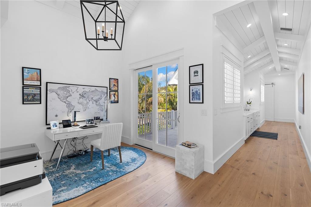 Office area featuring light wood finished floors, a chandelier, and a high wood beamed ceiling