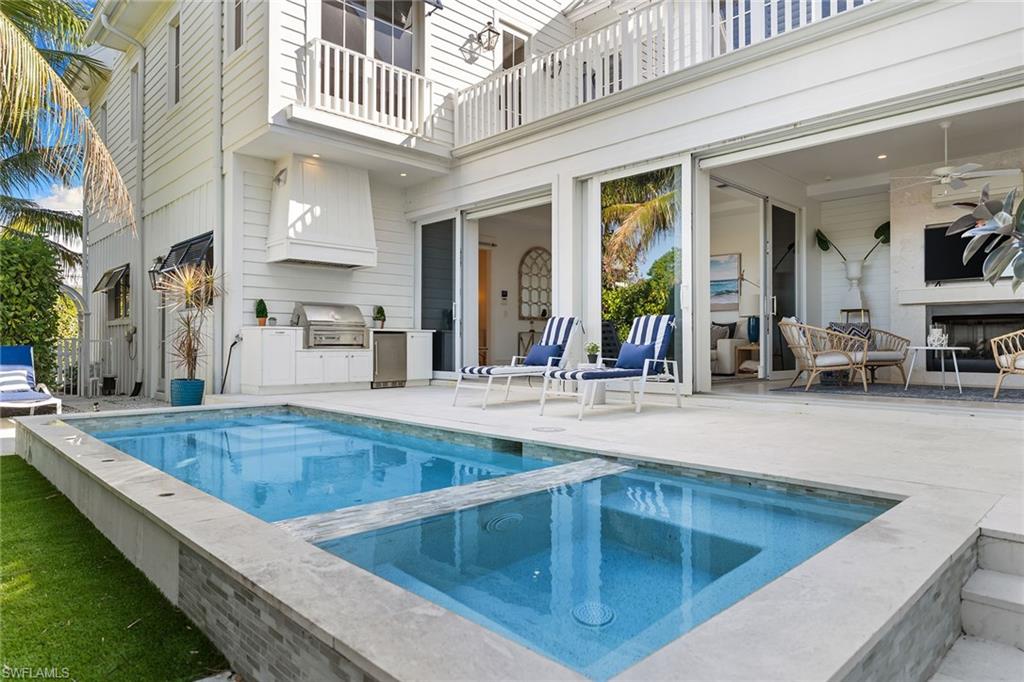 Integrated pool / hot tub featuring a balcony, an outdoor kitchen, and a patio area