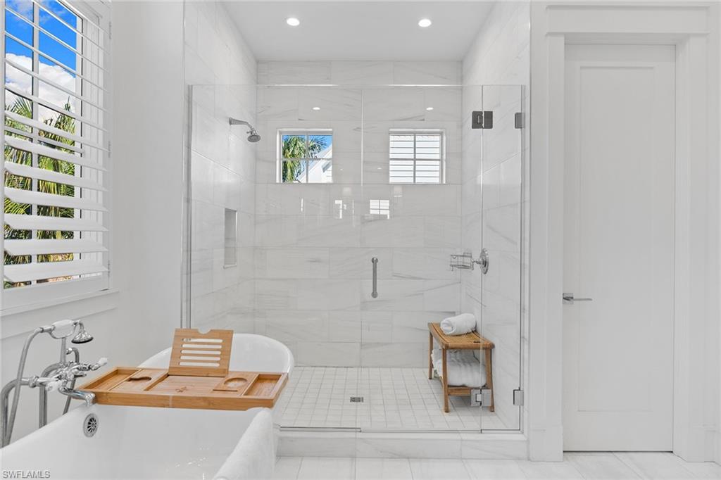 Bathroom featuring a stall shower, a freestanding tub, and recessed lighting