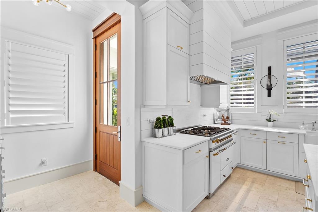 Kitchen featuring white cabinets, custom range hood, and white gas stovetop