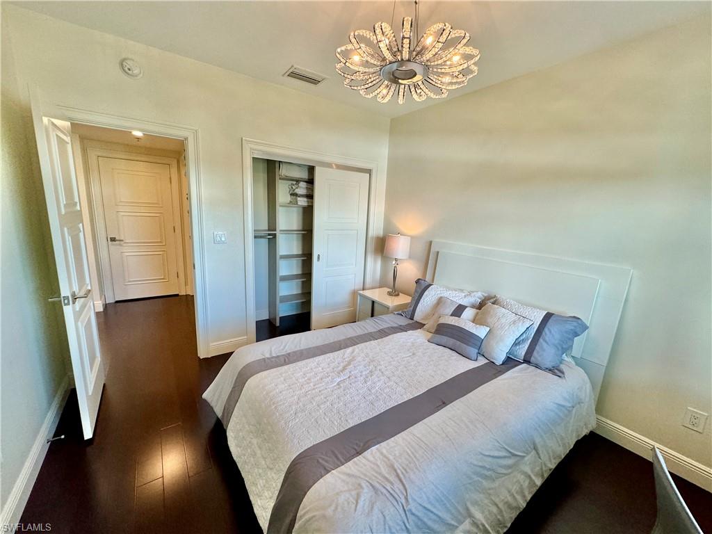 Bedroom featuring an inviting chandelier, a closet, and dark wood-type flooring