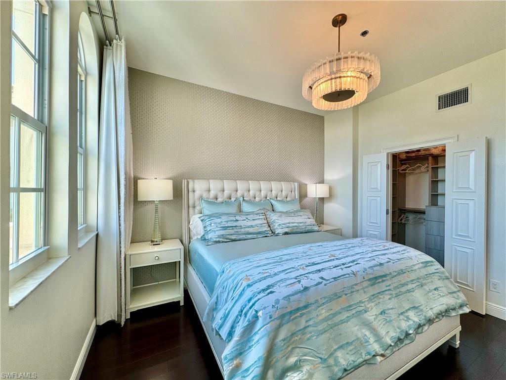 Bedroom with a walk in closet, a closet, and dark wood-type flooring