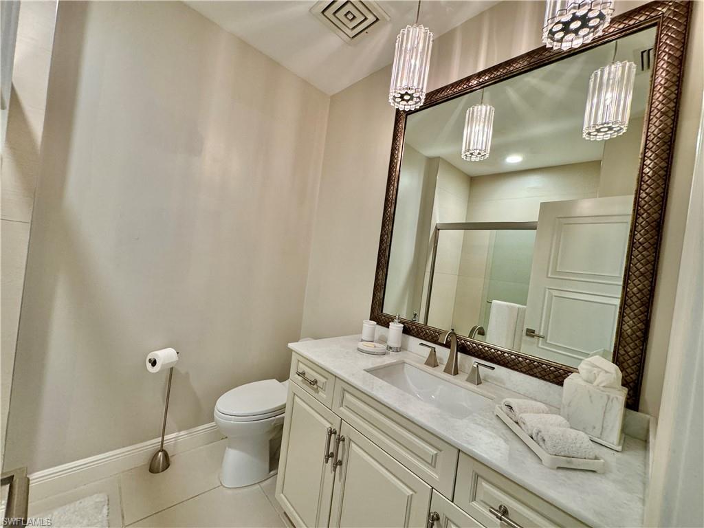 Bathroom with toilet, tile patterned flooring, vanity, and a shower with door
