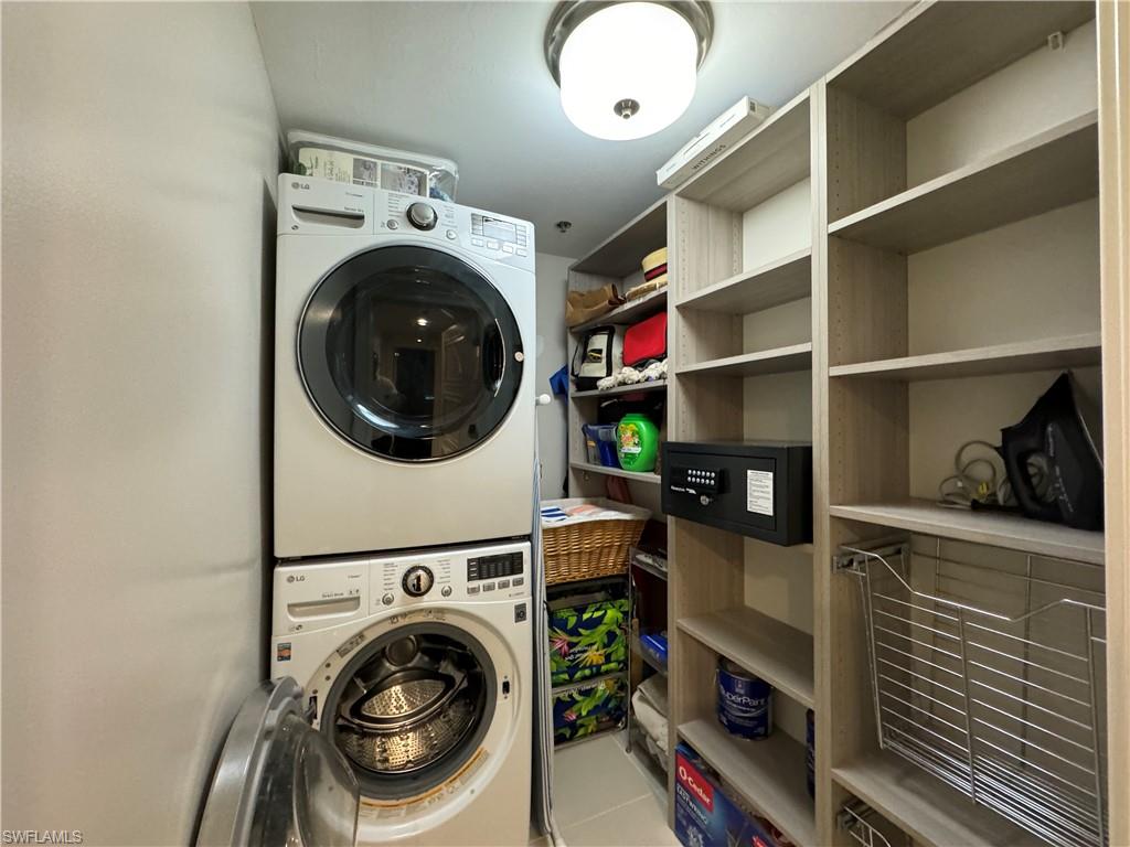 Washroom featuring stacked washer / drying machine and tile patterned flooring