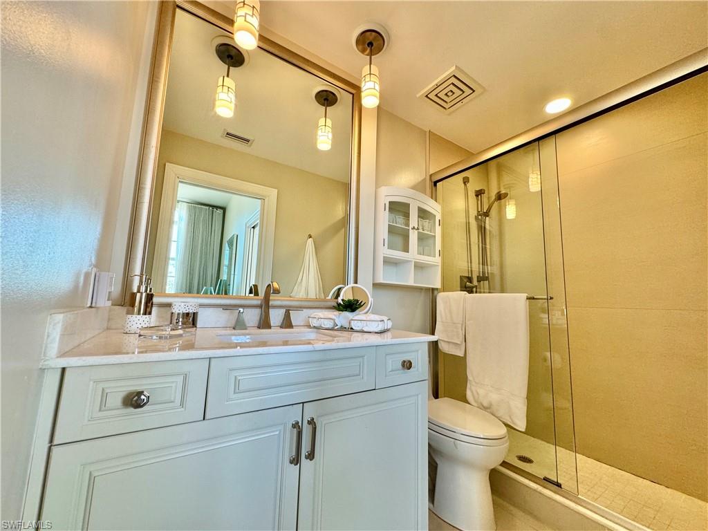 Bathroom featuring a shower with door, vanity, and toilet