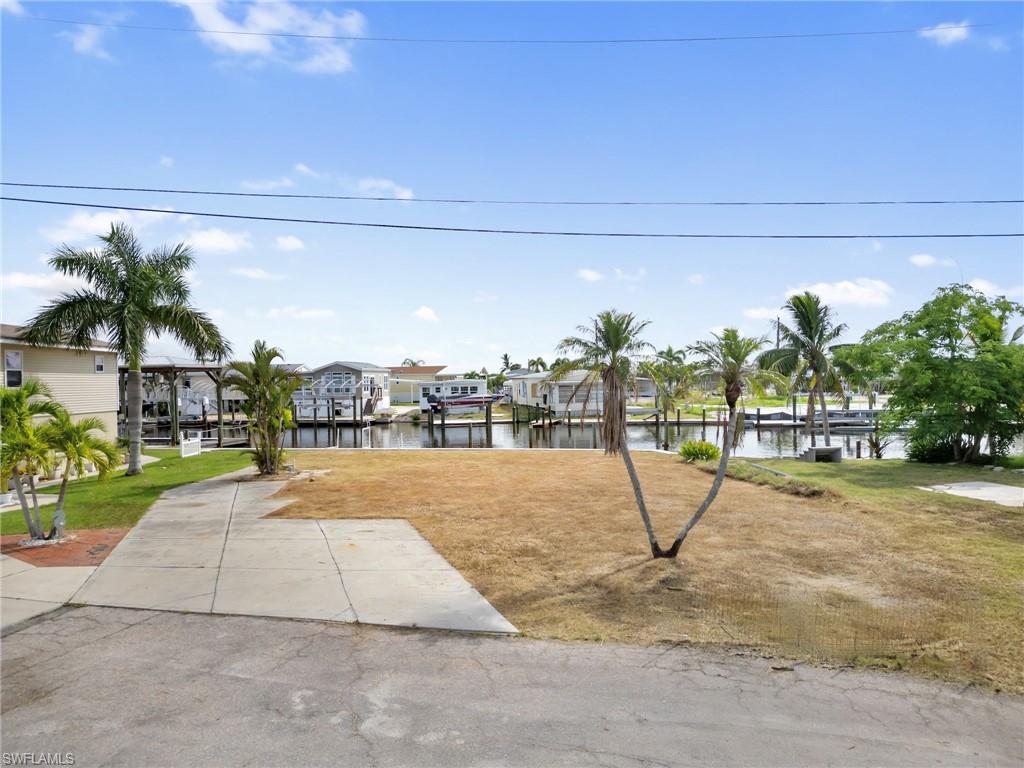 View of grassy yard with a water view, a boat dock, and a residential view