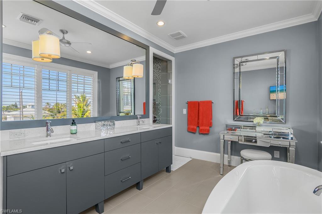 Full bath with double vanity, crown molding, a freestanding bath, a ceiling fan, and recessed lighting