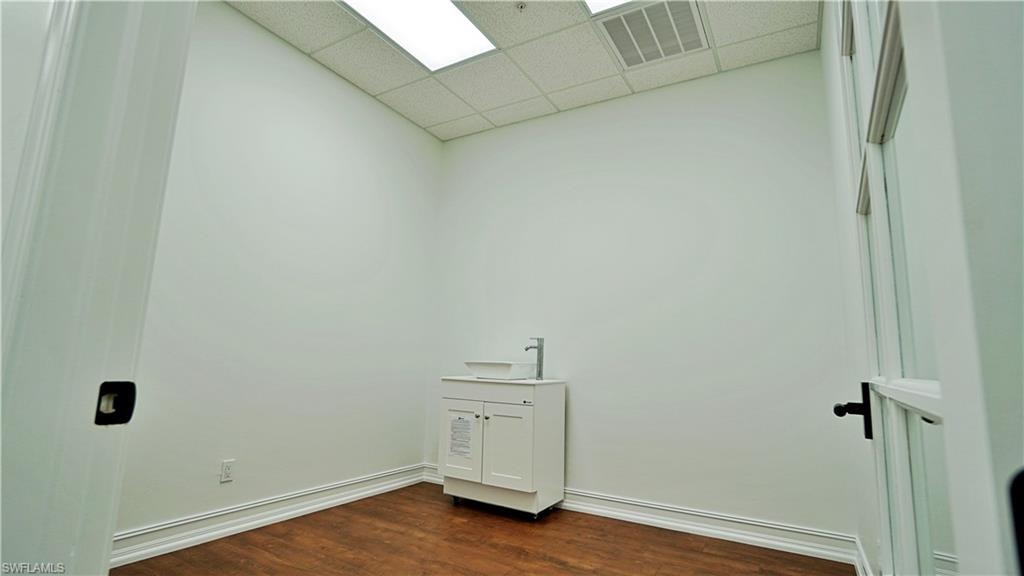 Laundry area featuring a paneled ceiling and dark wood-style flooring