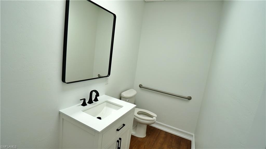 Half bath with vanity and dark wood-style flooring