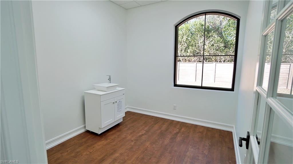 Empty room featuring dark wood finished floors and a drop ceiling