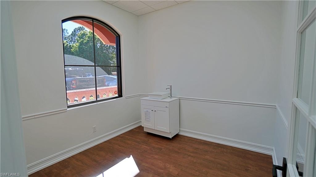 Empty room featuring dark wood-style flooring and a drop ceiling