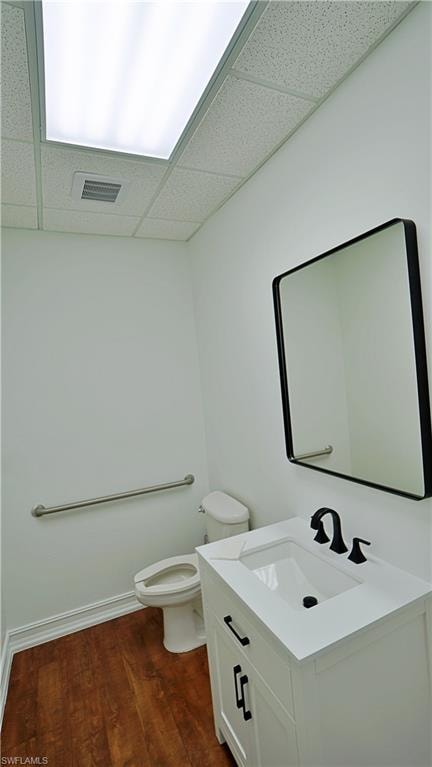 Bathroom with a paneled ceiling, vanity, and dark wood-style flooring