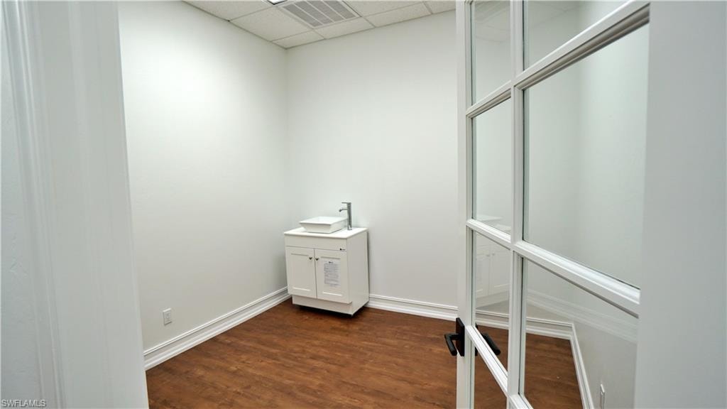 Bathroom with a paneled ceiling, dark wood-type flooring, and vanity