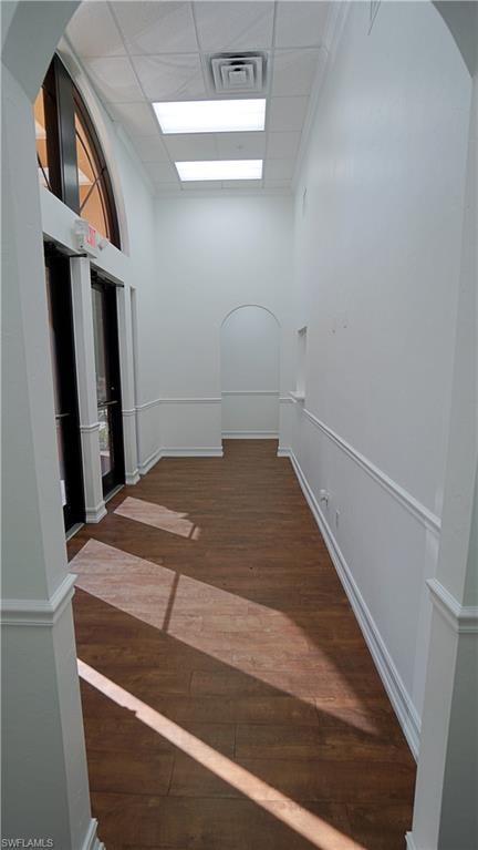 Hallway with dark wood finished floors and a drop ceiling