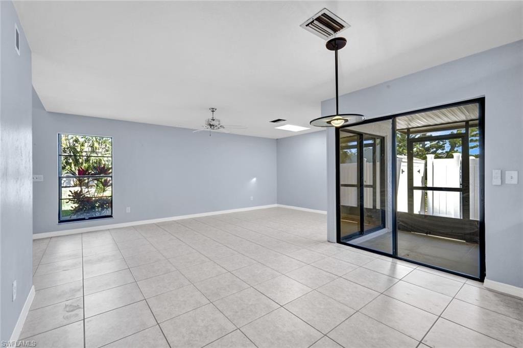 Unfurnished room featuring a ceiling fan, plenty of natural light, and light tile patterned floors