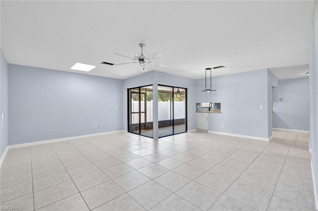 Unfurnished room with ceiling fan, light tile patterned floors, and a skylight