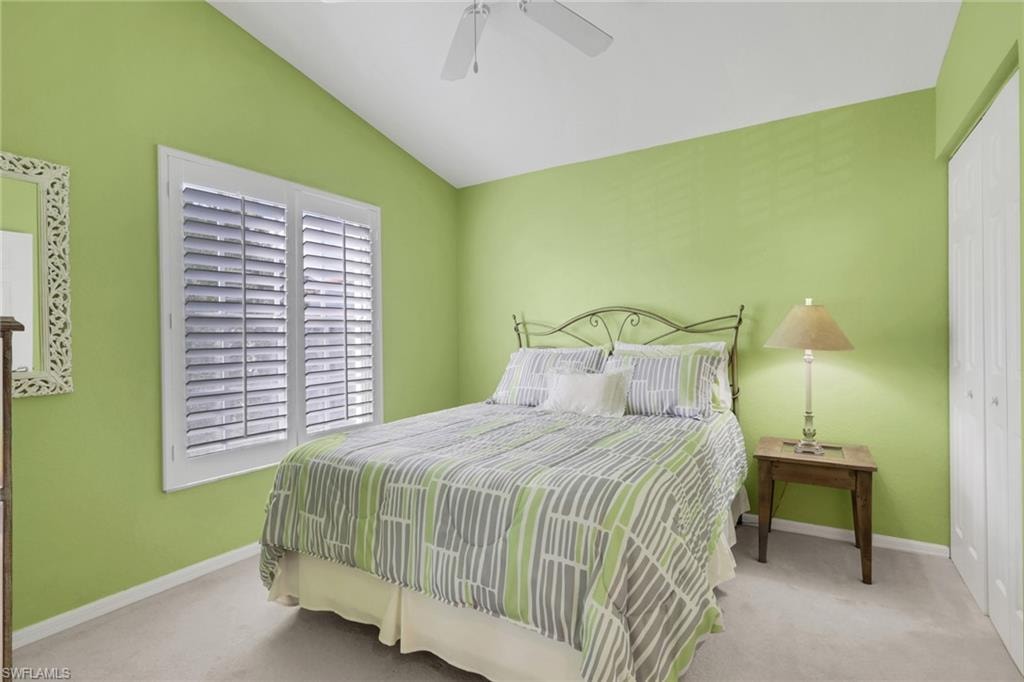 Bedroom featuring  plantation shutters, walk in closet, light colored carpet,  and a ceiling fan