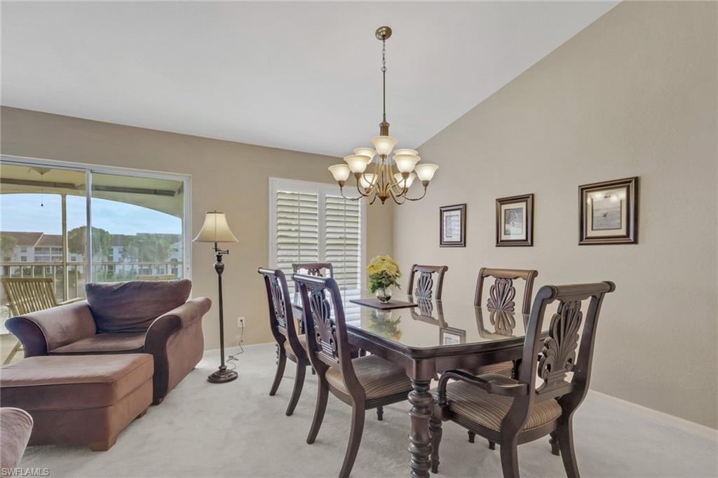 Dining space featuring a chandelier, plantation shutters,  vaulted ceiling, and plenty of natural light with lake view